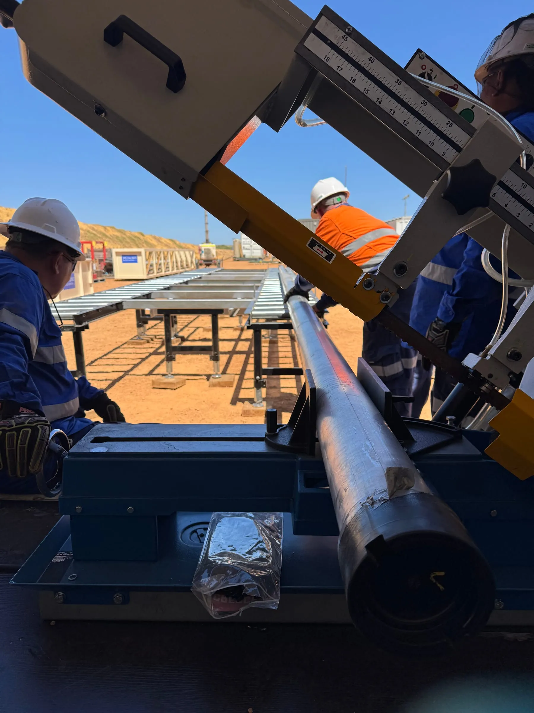 Crew cutting a core barrel to length with a band saw on the processing tables