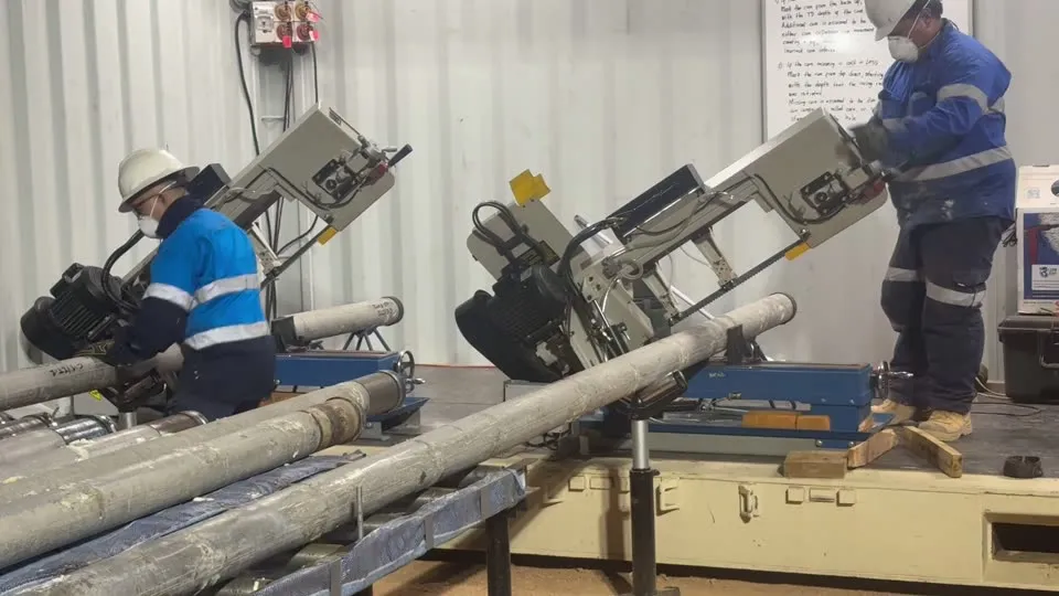 Two engineers cutting core to length with twin band saws in the processing container