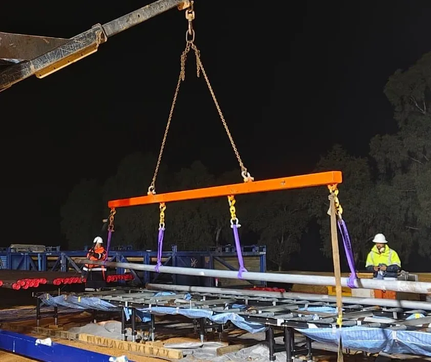 Inner barrels lifted onto the processing tables on a spreader beam at night