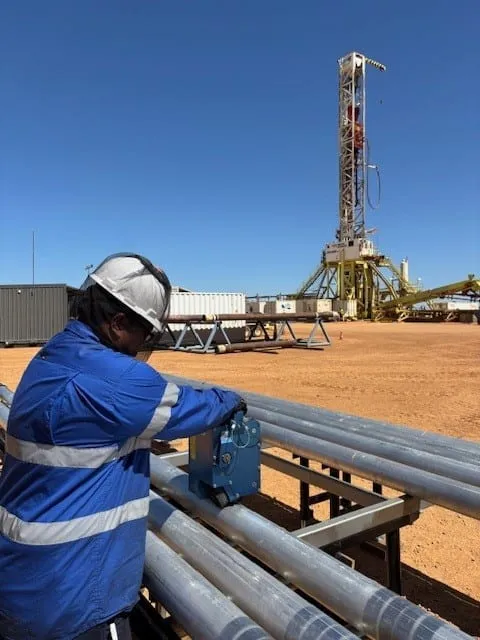 Engineer running a gamma logger along core barrels on the tables, the rig behind