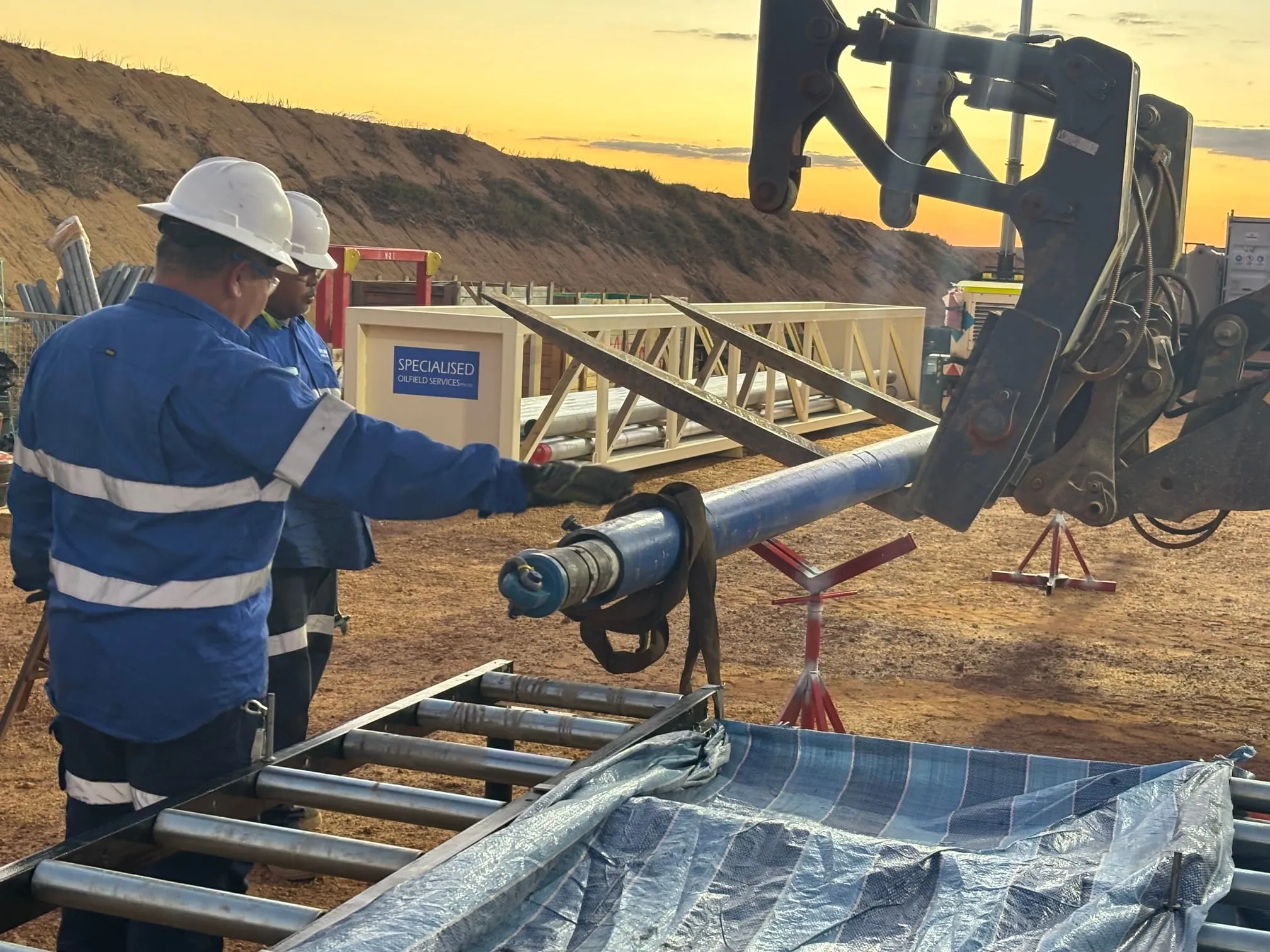 Crew guiding an inner barrel onto the processing tables at sunset