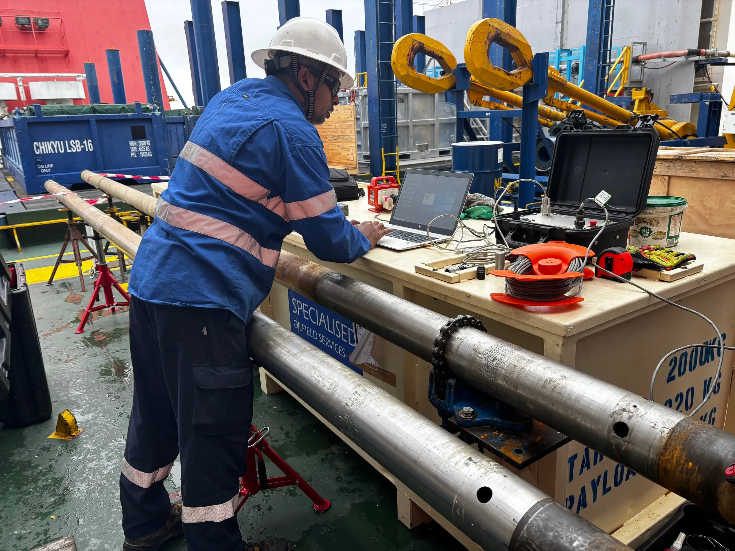 Engineer watching SureCore data on a laptop set up on deck beside the core barrels